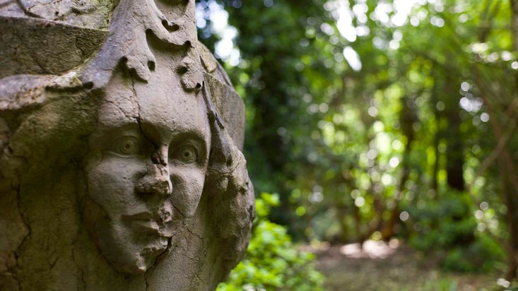 Close up of a face mask on a volcanic stone ornamental urn at Hare Hill, Cheshire.